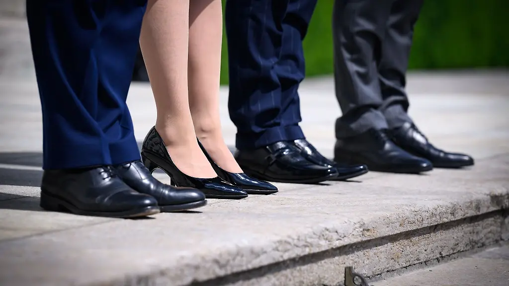 Eine-Frau-steht-zwischen-drei-Maennern-in-Anzuegen-auf-Treppenstufen