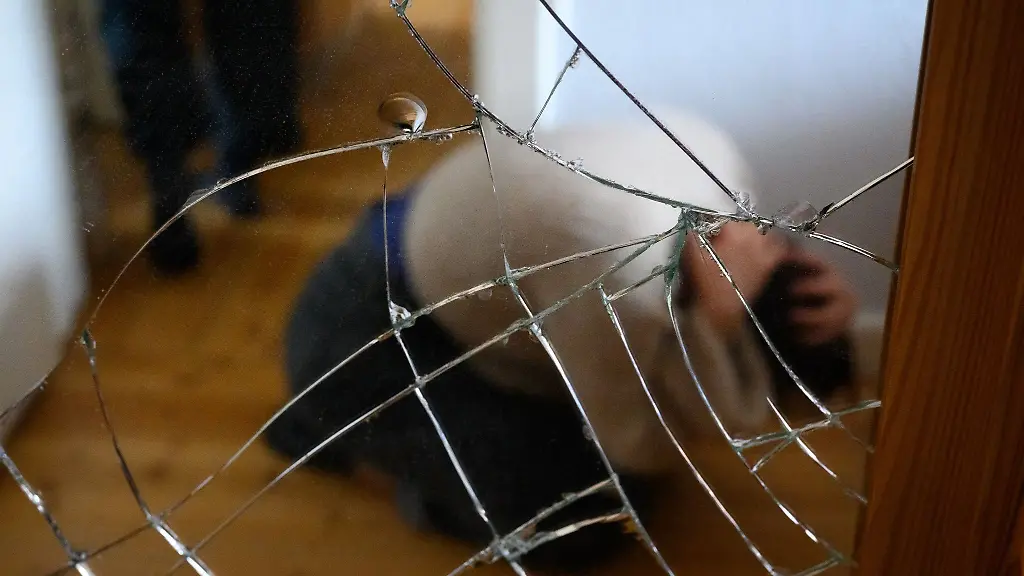 Eine-Frau-duckt-sich-hinter-einer-zerbrochenen-Scheibe