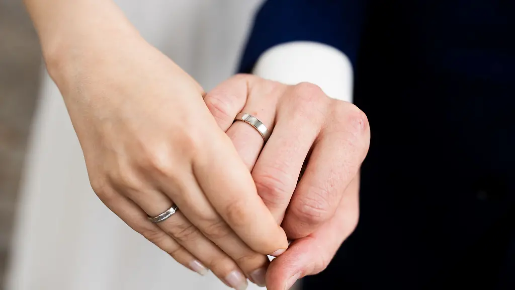 Ein-frisch-vermaehltes-Brautpaar-zeigt-nach-der-Eheschliessung-im-Rathaus-die-Eheringe