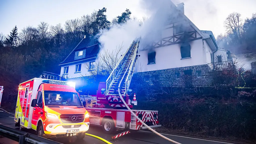 Einsatzkraefte-der-Feuerwehr-bekaempfen-einen-Brand-in-einem-Wohnhaus