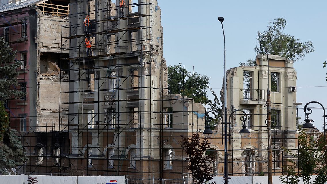 An einem beinahe komplett zerbombten Haus in Mariupol finden Arbeiten zum Wiederaufbau statt.