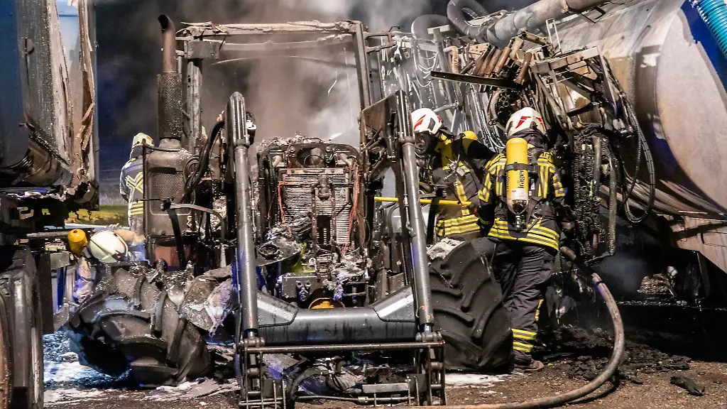 Feuerwehrleute-stehen-zwischen-verbrannten-landwirtschaftlichen-Geraeten