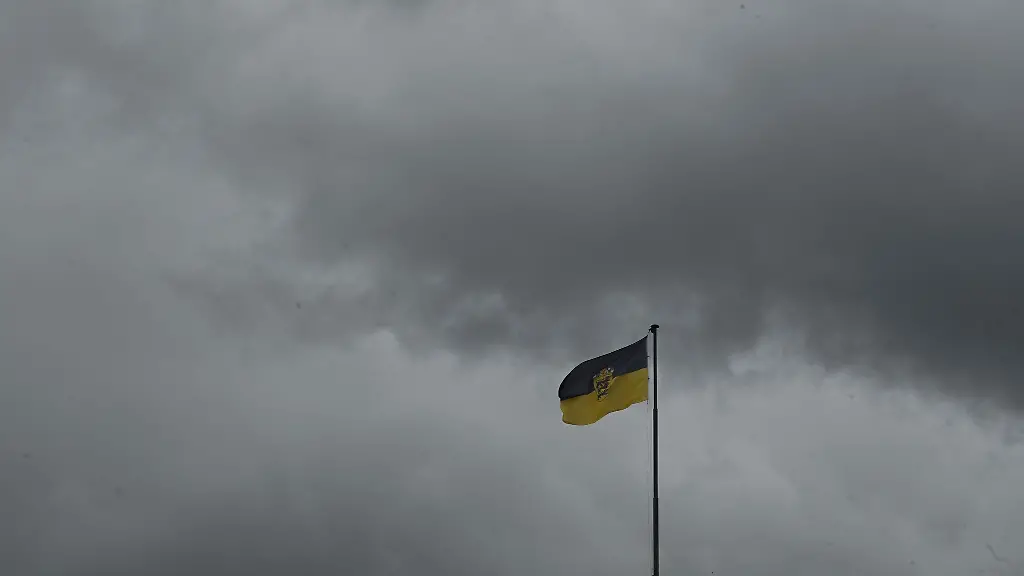 Dunkle-Regenwolken-ziehen-ueber-das-Neue-Schloss-auf-dem-die-Flagge-von-Baden-Wuerttemberg-weht