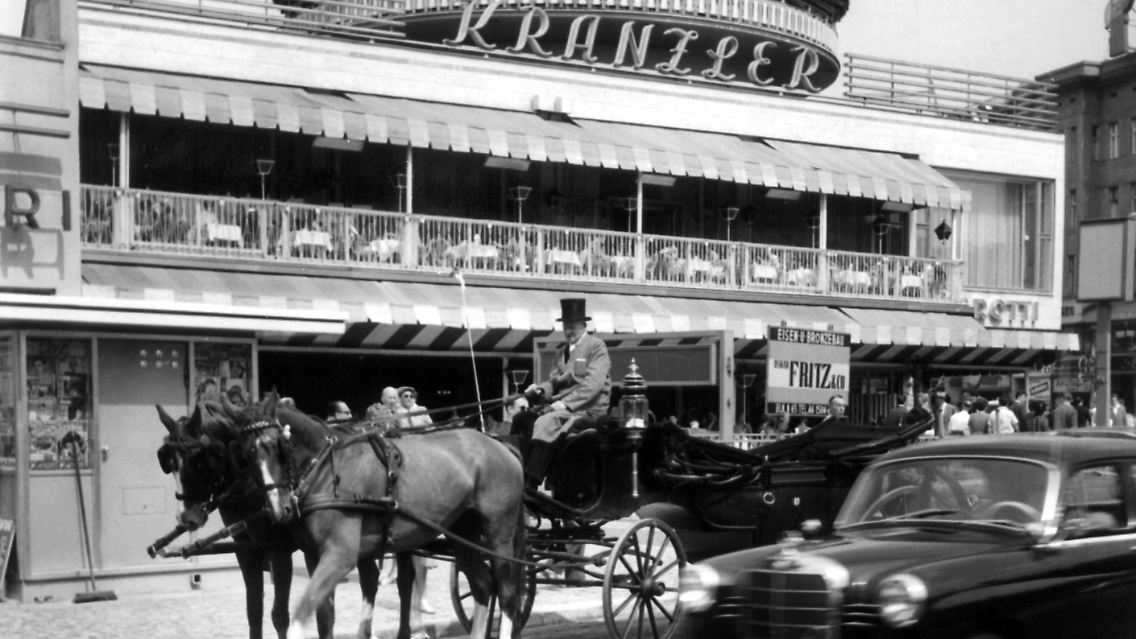 Ein Bild aus vergangenen Zeiten: Eine Pferdekutsche und eine Mercedes-Limousine auf dem Kurfürstendamm vor dem berühmten Cafe Kranzler (1960).