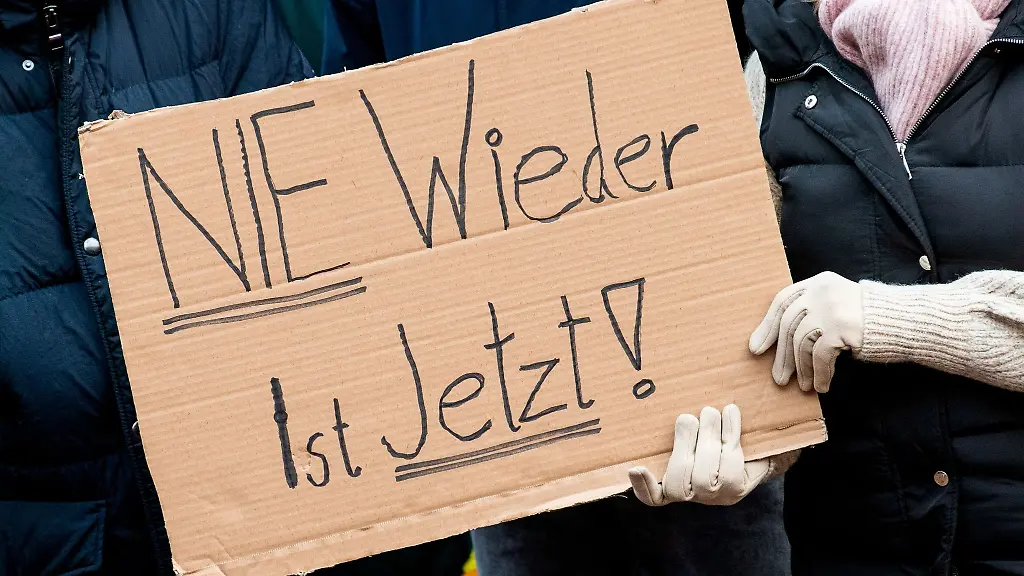 Teilnehmer-einer-Demonstration-gegen-Rechtsextremismus-halten-ein-Schild-Nie-wieder-ist-jetzt