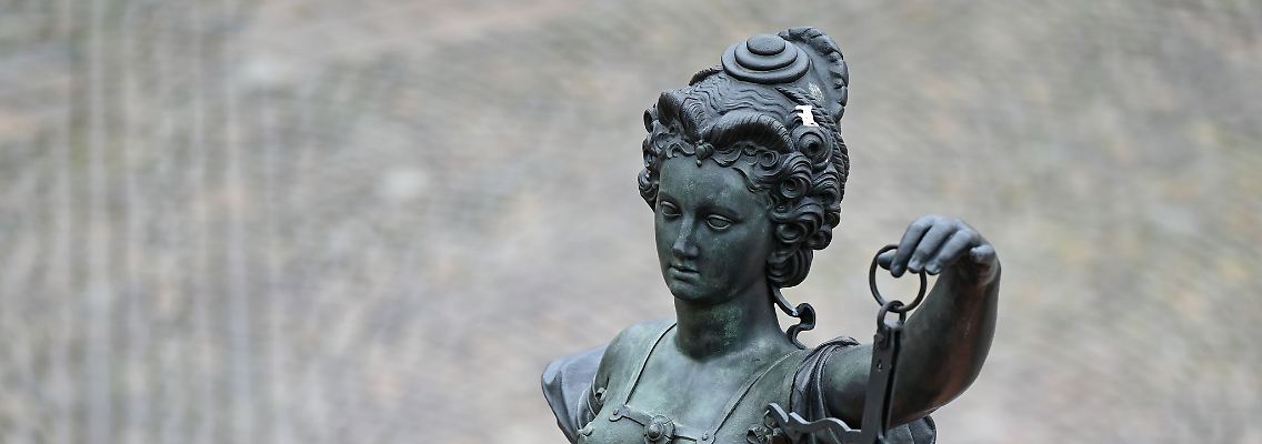 Eine Statue der Justitia hält eine Waage und ein Schwert in der Hand.
