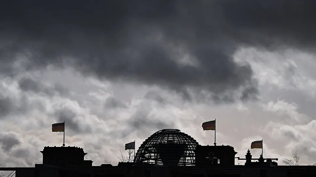Wolken-sind-ueber-der-Kuppel-vom-Reichstag-zu-sehen-auf-dem-Deutschlandfahnen-wehen