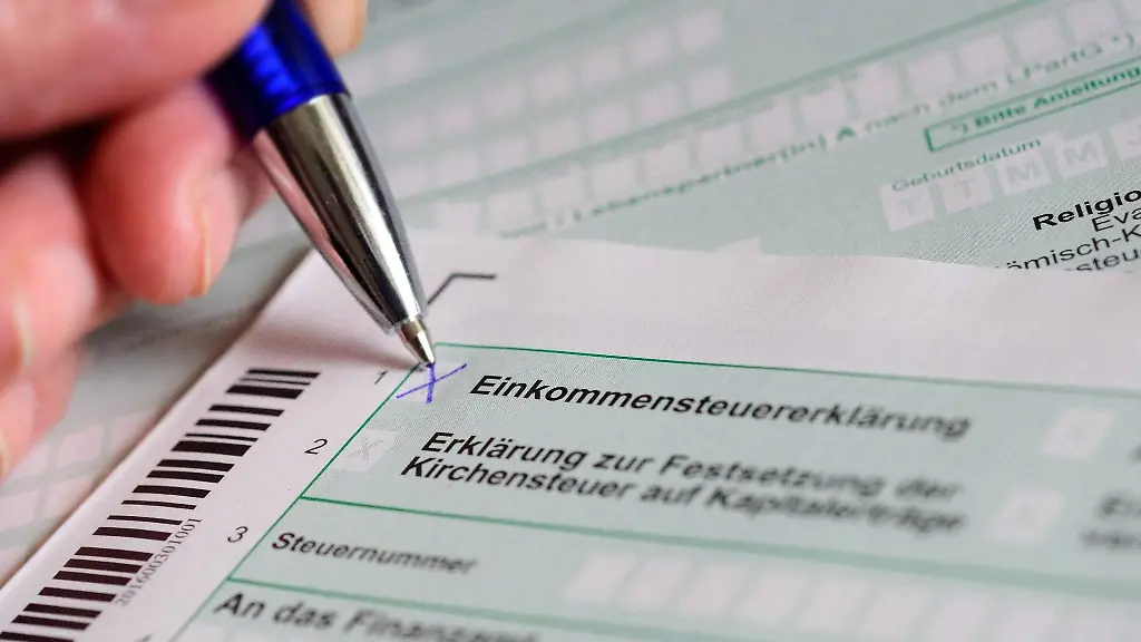 Eine-Hand-mit-Kugelschreiber-setzt-ein-Kreuz-bei-Einkommensteuererklaerung-auf-dem-offiziellen-Formular-des-Finanzamts