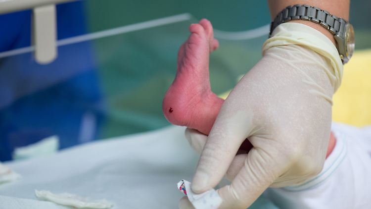 Eine Krankenschwester entnimmt einem Säugling an der Ferse Blut für eine Untersuchung.