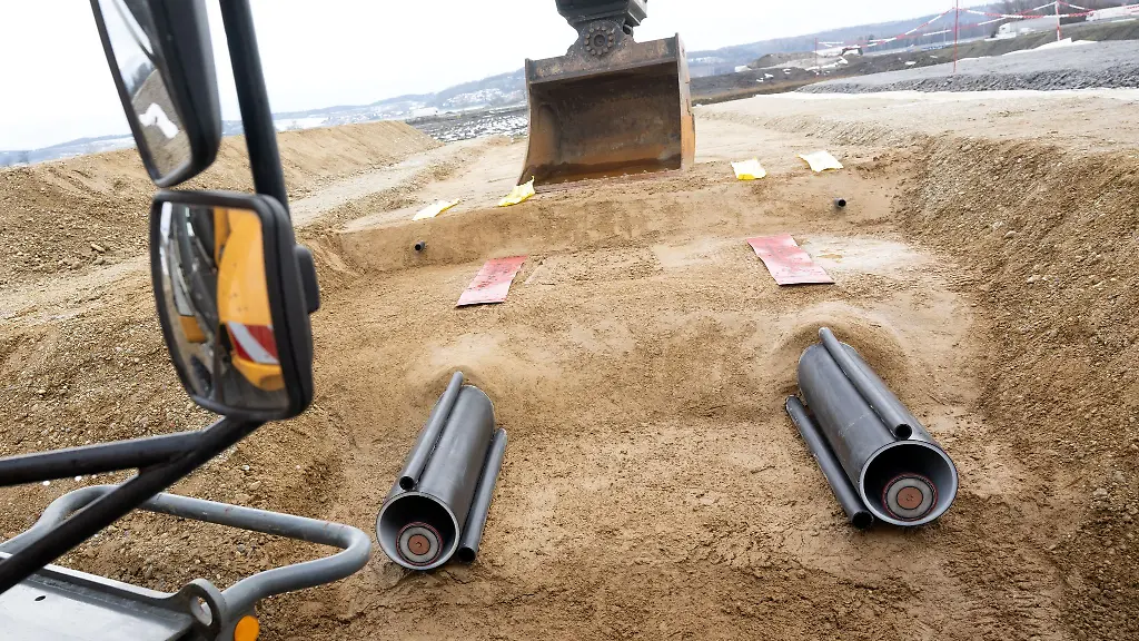 Ein-Bagger-und-zwei-Kabel-sind-waehrend-der-symbolischen-Baustelleneroeffnung-fuer-die-Baumassnahmen-des-Suedostlinks-zu-sehen