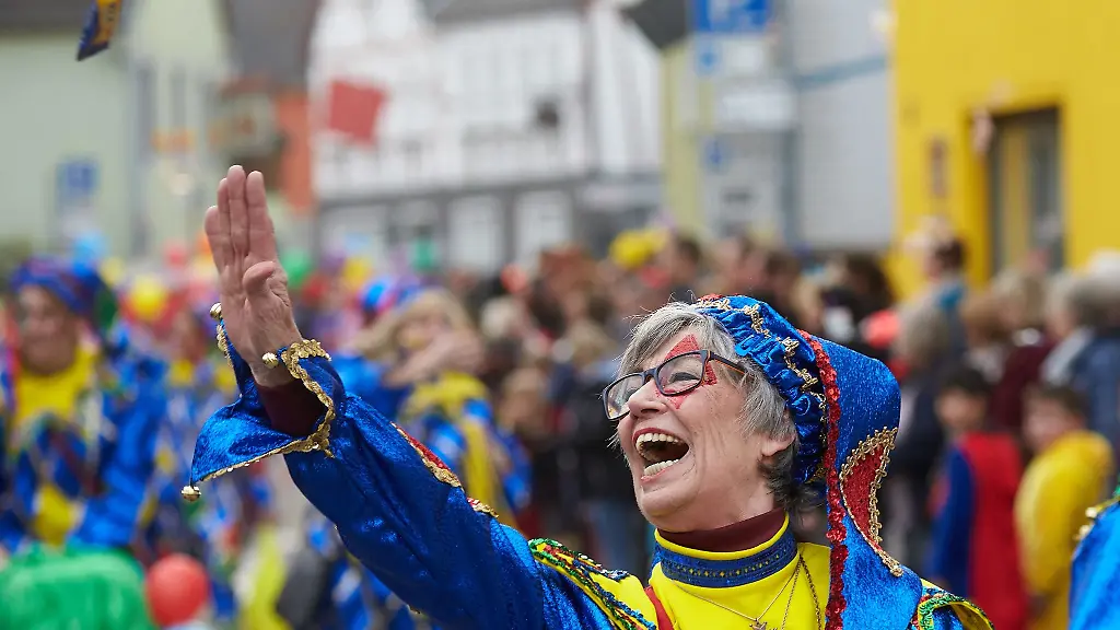 Naerrinnen-in-bunten-Kostuemen-tanzen-zur-Weiberfastnacht-in-den-Strassen