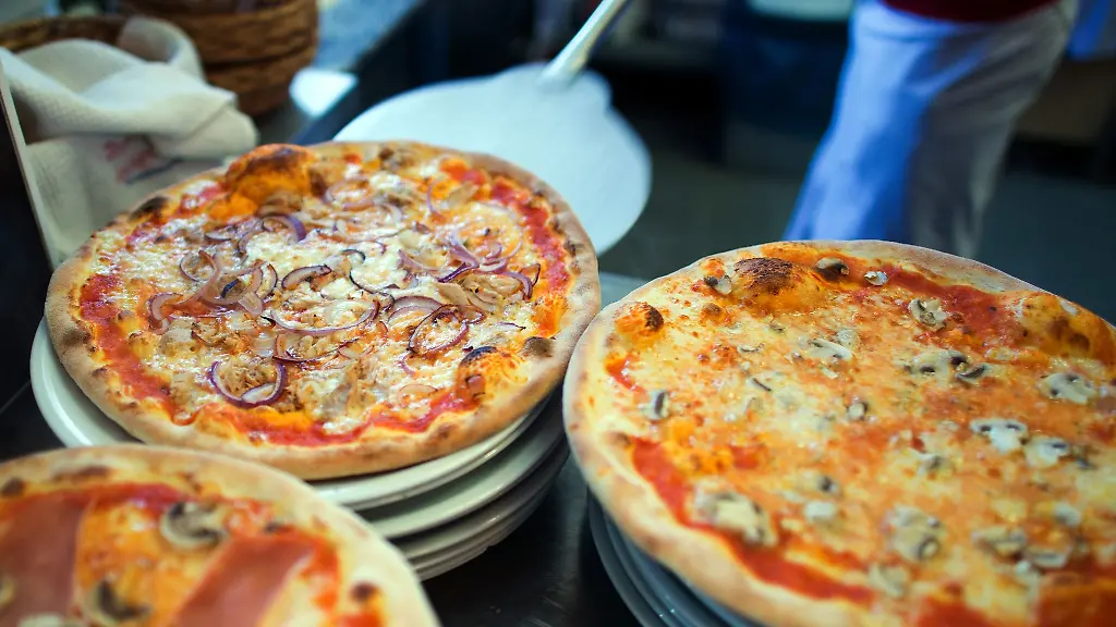 In-einer-Pizzeria-liegen-fertige-Pizzen-auf-Tellern