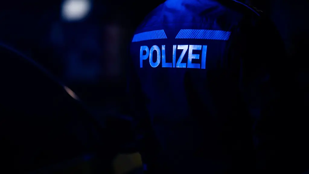 Ein-Polizist-steht-neben-einem-Polizeiauto