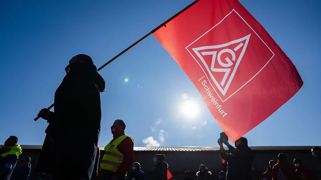 Ein-Metaller-nimmt-mit-einer-Gewerkschaftsfahne-an-einer-Kundgebung-teil