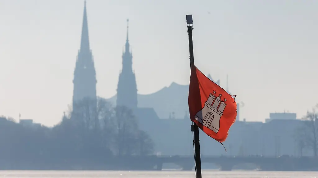 Die-Hamburg-Fahne-weht-vor-dem-diesigen-Panorama-von-Nikolaikirche-Rathausturm-und-Elbphilharmonie