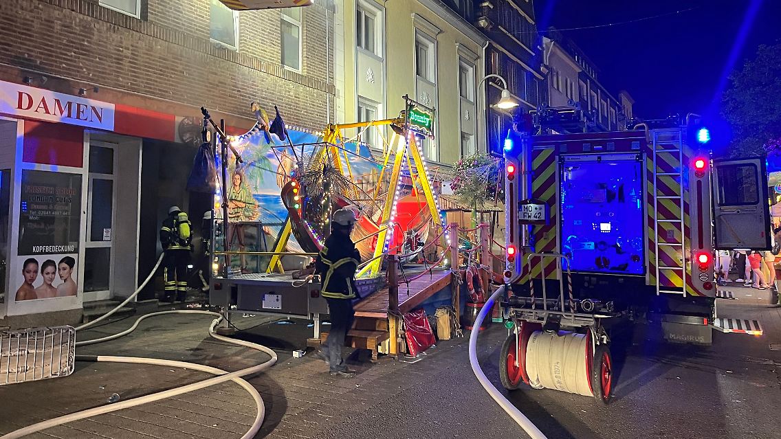 Die Feuerwehrschläuche schlängeln sich um ein Fahrgeschäft.