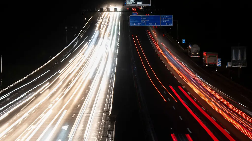 Vorbeifahrende-Autos-ziehen-in-der-Dunkelheit-ihre-Lichtspuren-ueber-die-Autobahn-5-bei-Frankfurt