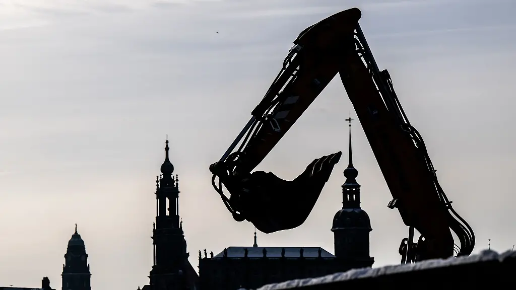 Die-Schaufel-eines-Baggers-auf-einer-Baustelle-am-Elberadweg-ist-vor-dem-Rathaus-l-r-der-Hofkirche-und-dem-Hausmannsturm-zu-sehen