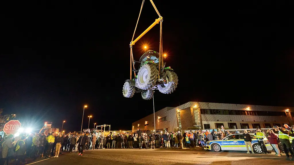 Ein-Traktor-schwebt-an-einem-Kran-haengend-vor-einem-Lidl-Zentrallager