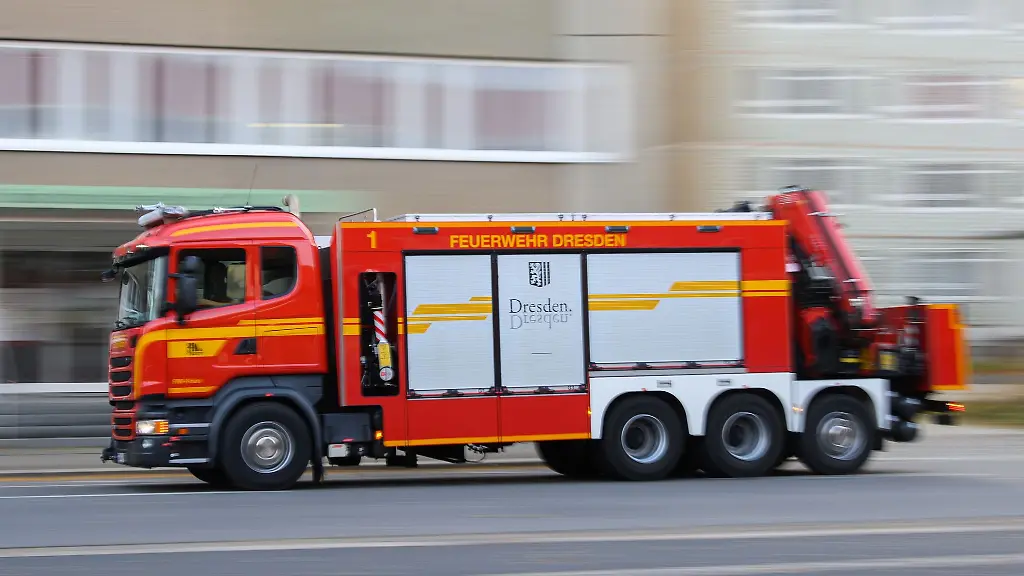 Ein-Ruestwagen-Kran-der-Berufsfeuerwehr-Dresden-faehrt-auf-einer-Strasse-zum-Einsatz