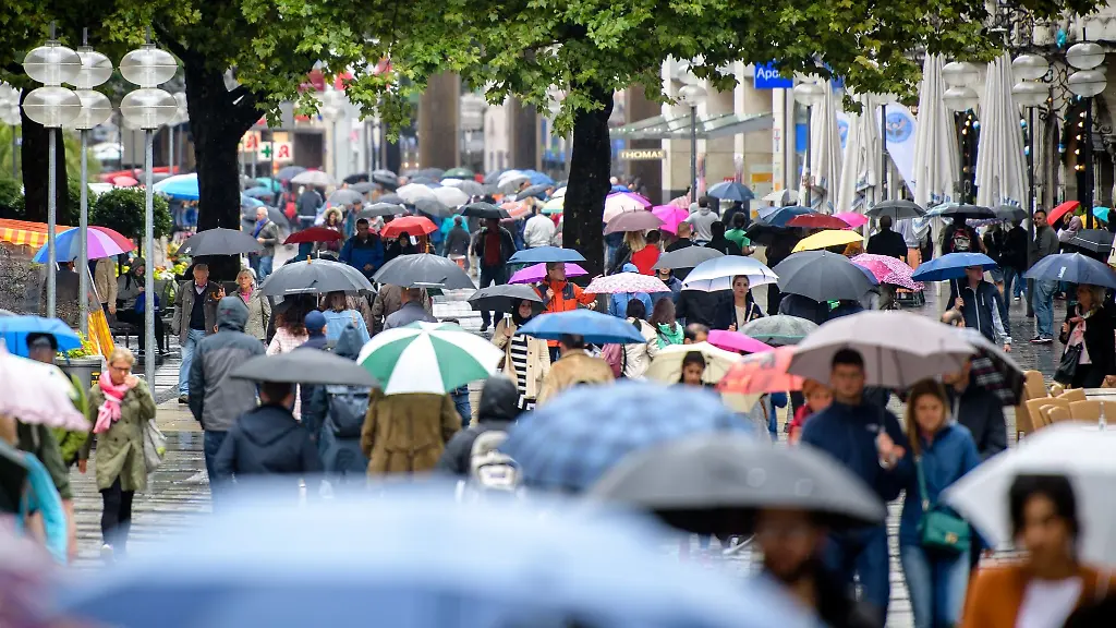 Passanten-mit-Regenschirmen-laufen-im-Regen-durch-die-Fussgaengerzone-Neuhauser-Strasse-und-Kaufingerstrasse