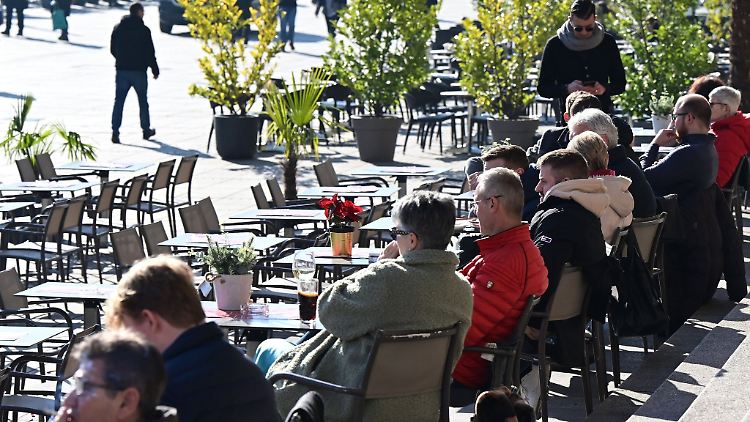 Bei strahlendem Sonnenschein sitzen Menschen in einem Freiluftcafe auf dem Schlossplatz in Stuttgart.