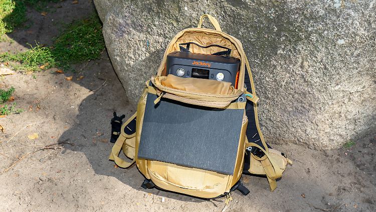 Der Jackery Solargenerator 300 Plus in der oberen Tasche eines Fotorucksacks. Das zusammengeklappte Solarpanel ist außen festgegurtet.