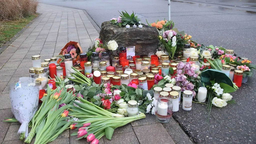 Blumen-und-Kerzen-zum-Gedenken-an-das-Opfer-liegen-vor-einer-Schule