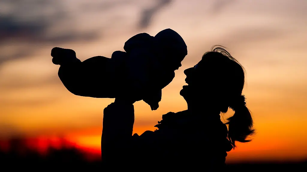 Eine-Mutter-hebt-ihr-Baby-in-die-Luft