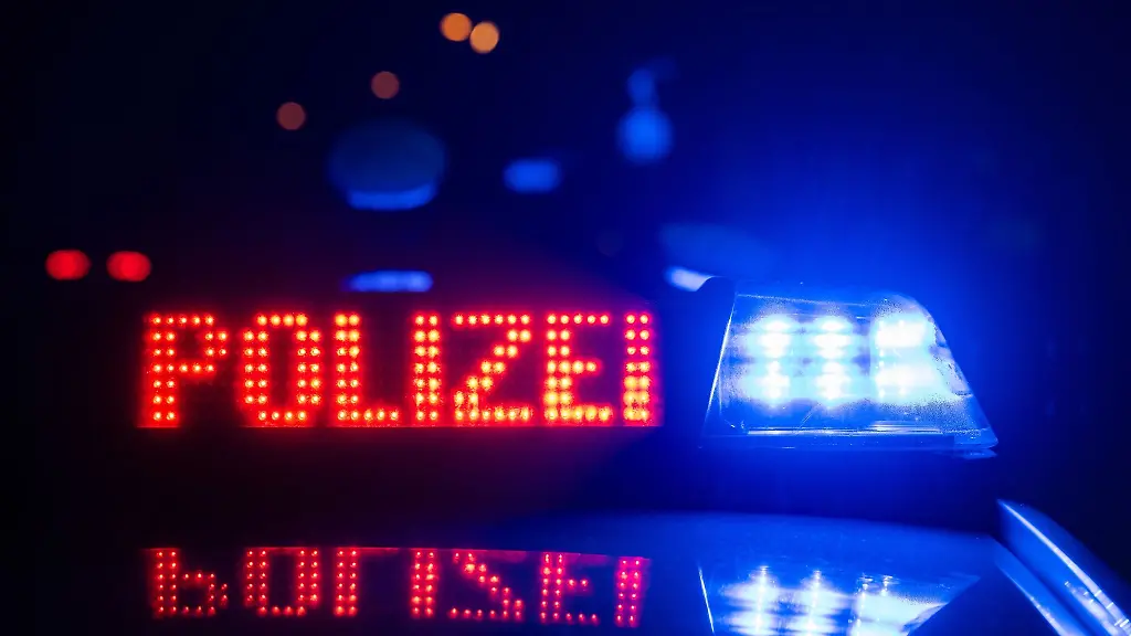 Zwei-Polizisten-stehen-im-Rahmen-eines-Fototermins-vor-einem-Polizeifahrzeug-gestellte-Szene
