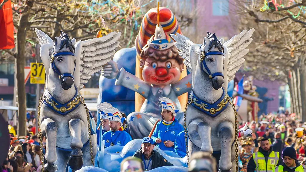 Verschiedene-Wagen-des-traditionellen-Rosenmontagsumzugs-fahren-durch-die-Stadt