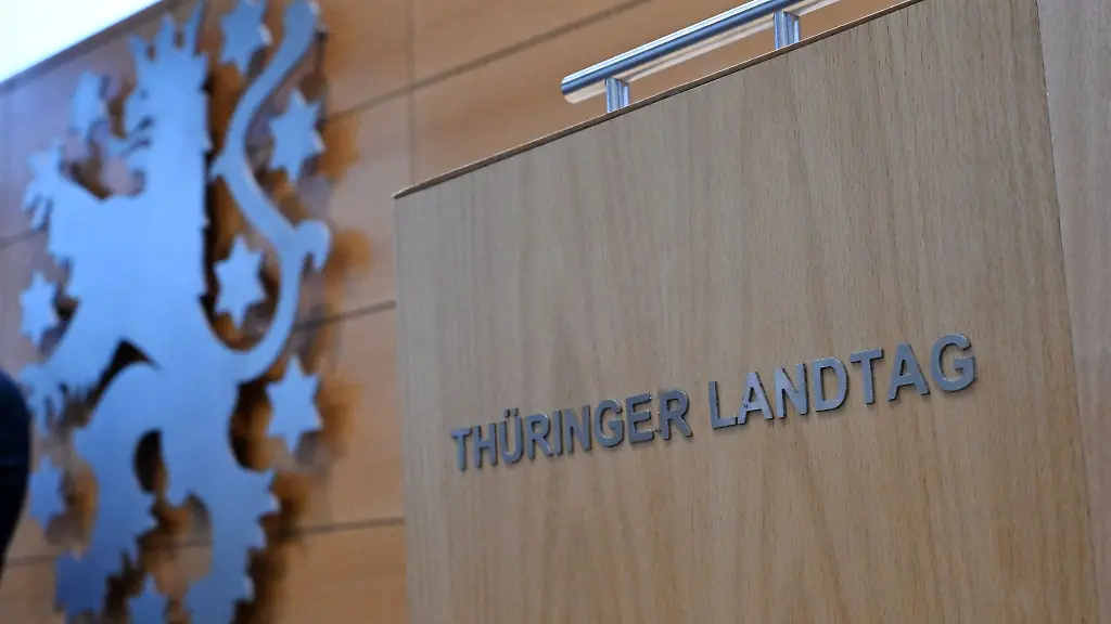 Eine-Wahlurne-mit-der-Aufschrift-Thueringer-Landtag-steht-neben-dem-Landeswappen-im-Plenarsaal-waehrend-der-Sitzung-des-Thueringer-Landtags
