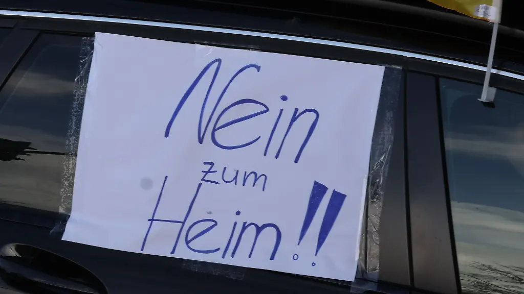 Ein-Blatt-Papier-mit-der-Aufschrift-Nein-zum-Heim-haengt-an-einem-Auto-bei-einem-Autokorso-gegen-die-geplante-Fluechtlingsunterkunft-am-ehemaligen-Wismut-Krankenhaus-durch-die-Innenstadt