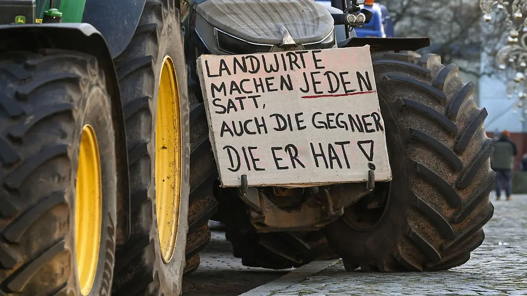 Ein-Protestplakat-mit-der-Aufschrift-Landwirte-mache-jeden-satt-auch-die-Gegner-die-er-hat-ist-an-einem-Traktor-befestigt