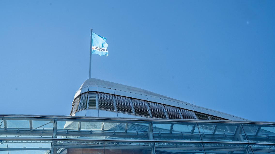 Türkisfarbene Flagge vor blauem Himmel.