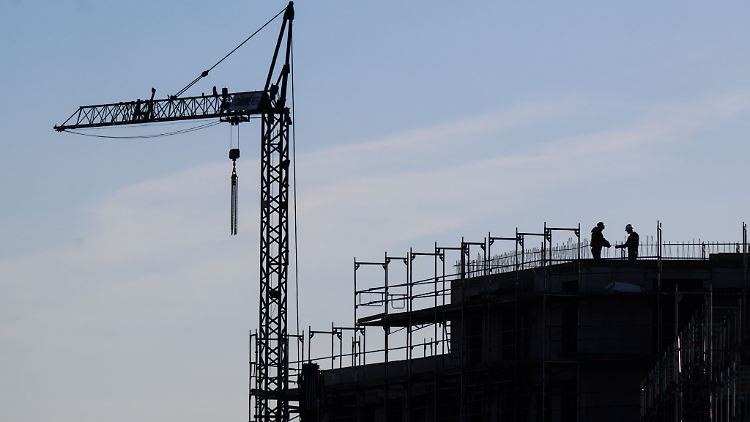 Bauarbeiter stehen auf der Baustelle eines Mehrfamilienhauses.