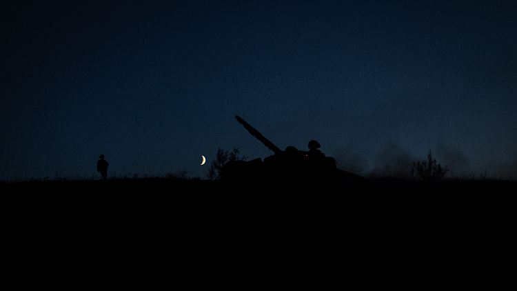 Ein kommandierender Soldat der 22. Brigade der Ukraine steht bei einer Nachtschießübung vor einem T-72-Panzer. 
