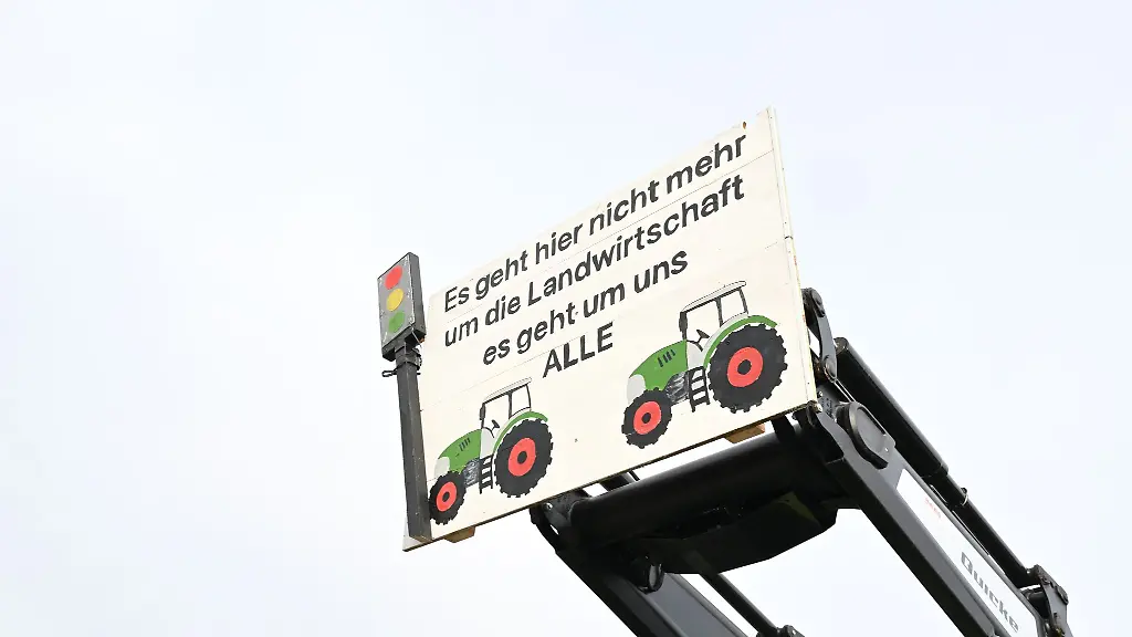 Mit-Traktoren-und-einem-Transparent-mit-der-Aufschrift-Es-geht-hier-nicht-mehr-um-die-Landwirtschaft-es-geht-um-uns-ALLE-demonstrieren-Landwirte-mit-Traktoren-gegen-die-Agrarpoltik-der-Bundesregierung