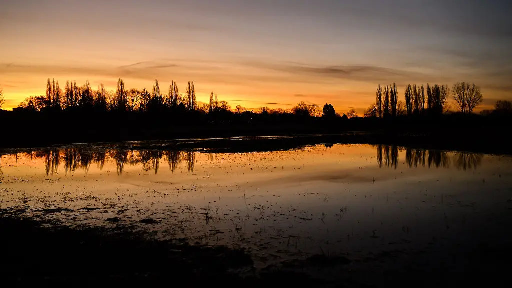 Der-Morgenhimmel-spiegelt-sich-in-der-noch-immer-vom-Hochwasser-und-hohem-Grundwasserspiegel-teilweise-gefluteten-Leinemasch-in-der-Region-Hannover