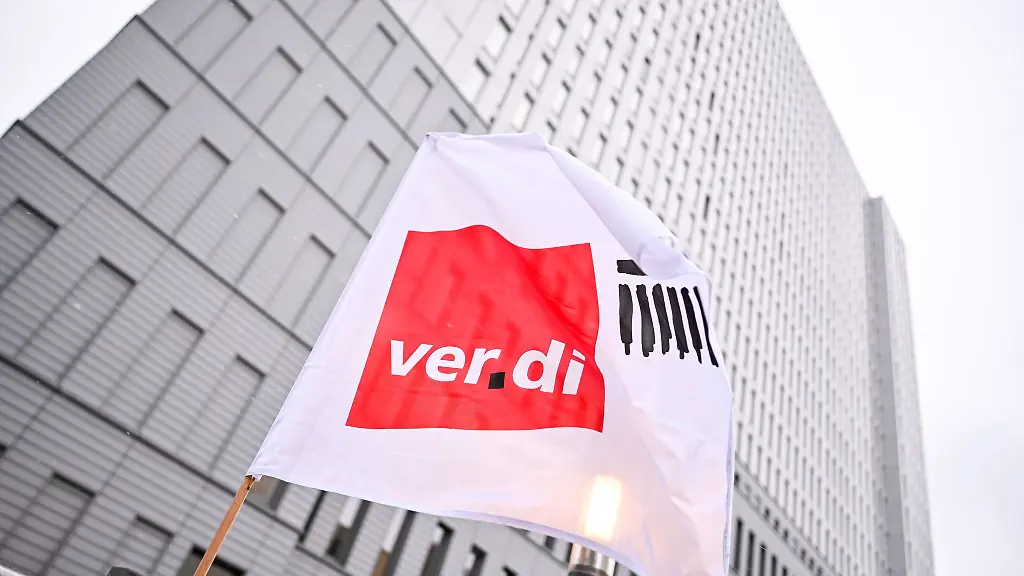 Eine-Flagge-von-Verdi-weht-bei-einem-Warnstreik-vor-einem-Hochhaus