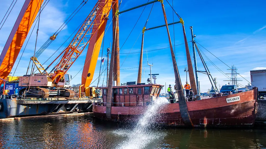 Wasser-wird-aus-dem-Rumpf-des-von-einem-Schwimmkran-angehobenen-Fischkutters-abgepumpt