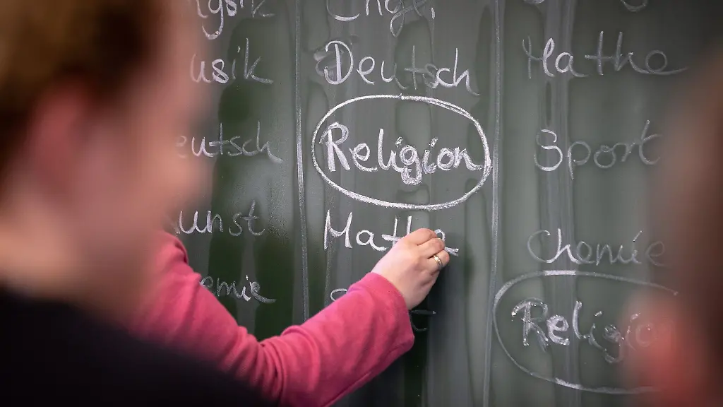 Eine-Lehrerin-schreibt-mit-Kreide-einen-Stundenplan-mit-Religionsunterricht-an-eine-Tafel
