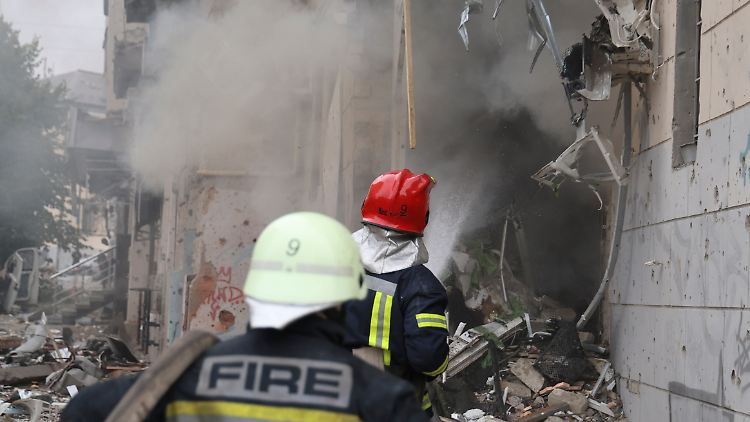 Einsatzkräfte der Feuerwehr versuchen die Flammen infolge des Raketenangriffs zu löschen.
