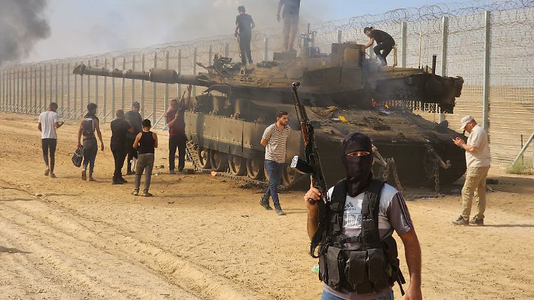 Kämpfer der Hamas führen an der Grenze einen erbeuteten israelischen Panzer vor.