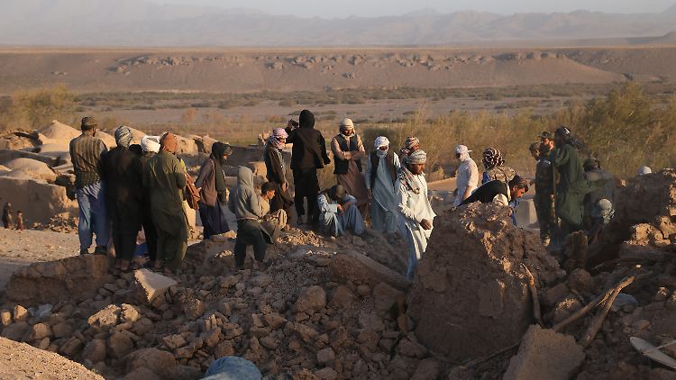 Menschen stehen in der afghanischen Provinz Herat in den Trümmern von Wohnhäusern.