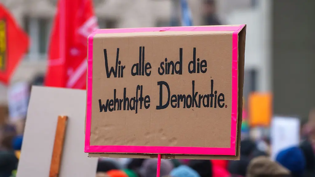 Ein-Plakat-Wir-alle-sind-die-wehrhafte-Demokratie-wird-auf-einer-Kundgebung-gezeigt