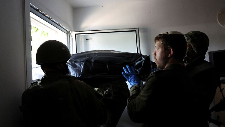 Israelische Soldaten tragen eine Leiche aus einem Haus in Kfar Asa.