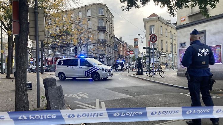 Die Polizei sperrt eine Straße, während ein Polizist hinter Absperrband Wache steht.