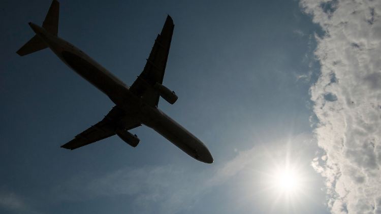 Vorbei an einem Wolkenfeld landet eine Passagiermaschine auf dem Flughafen.