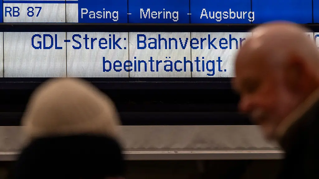 Bahnreisende-stehen-am-Hauptbahnhof-in-Muenchen-vor-einer-Anzeigetafel-mit-der-Aufschrift-GDL-Streik-Bahnverkehr-beeintraechtigt